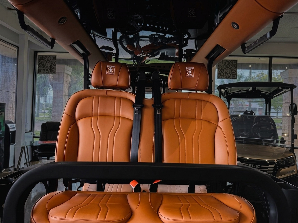 Cognac saddle-leather bucket seats with seat belts inside an ICON cart